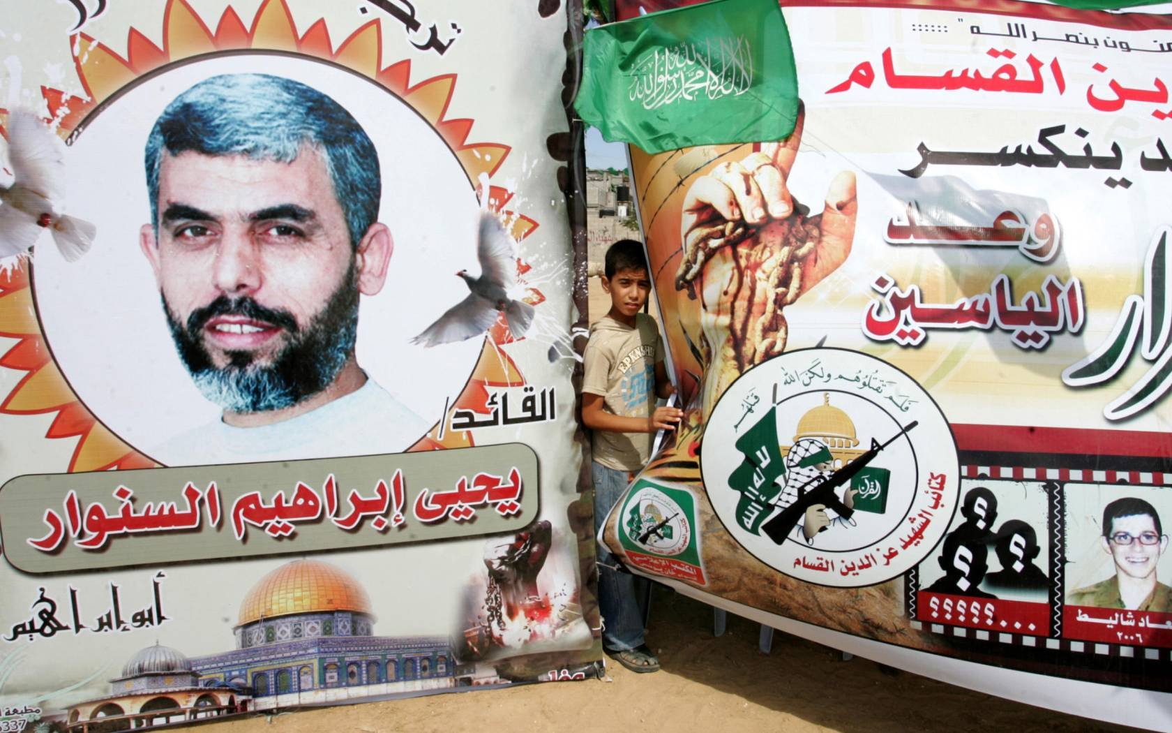 A young boy stands by a poster of Hamas leader Yahya Sinwar.